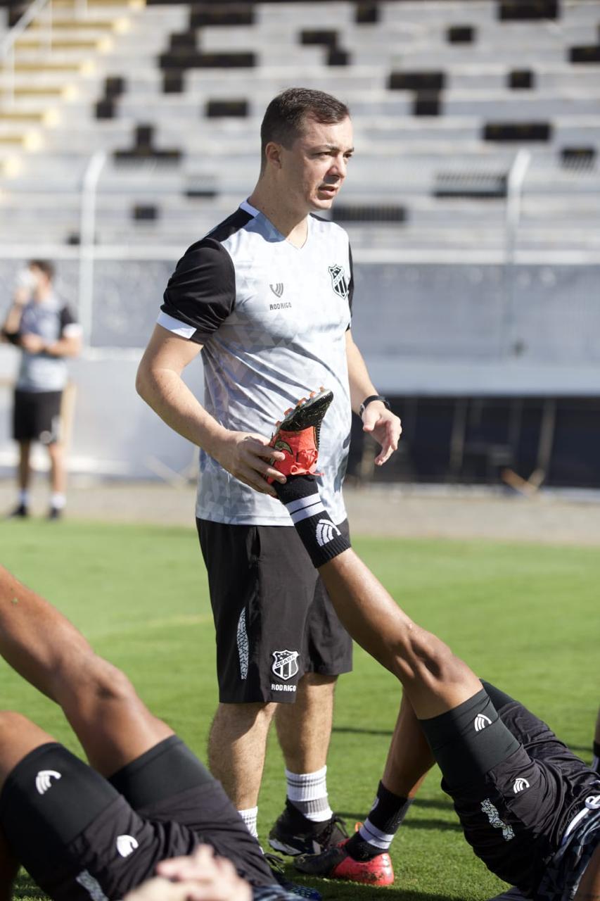 Dr. Rodrigo Oliveira conduzindo alongamento de atleta em estádio